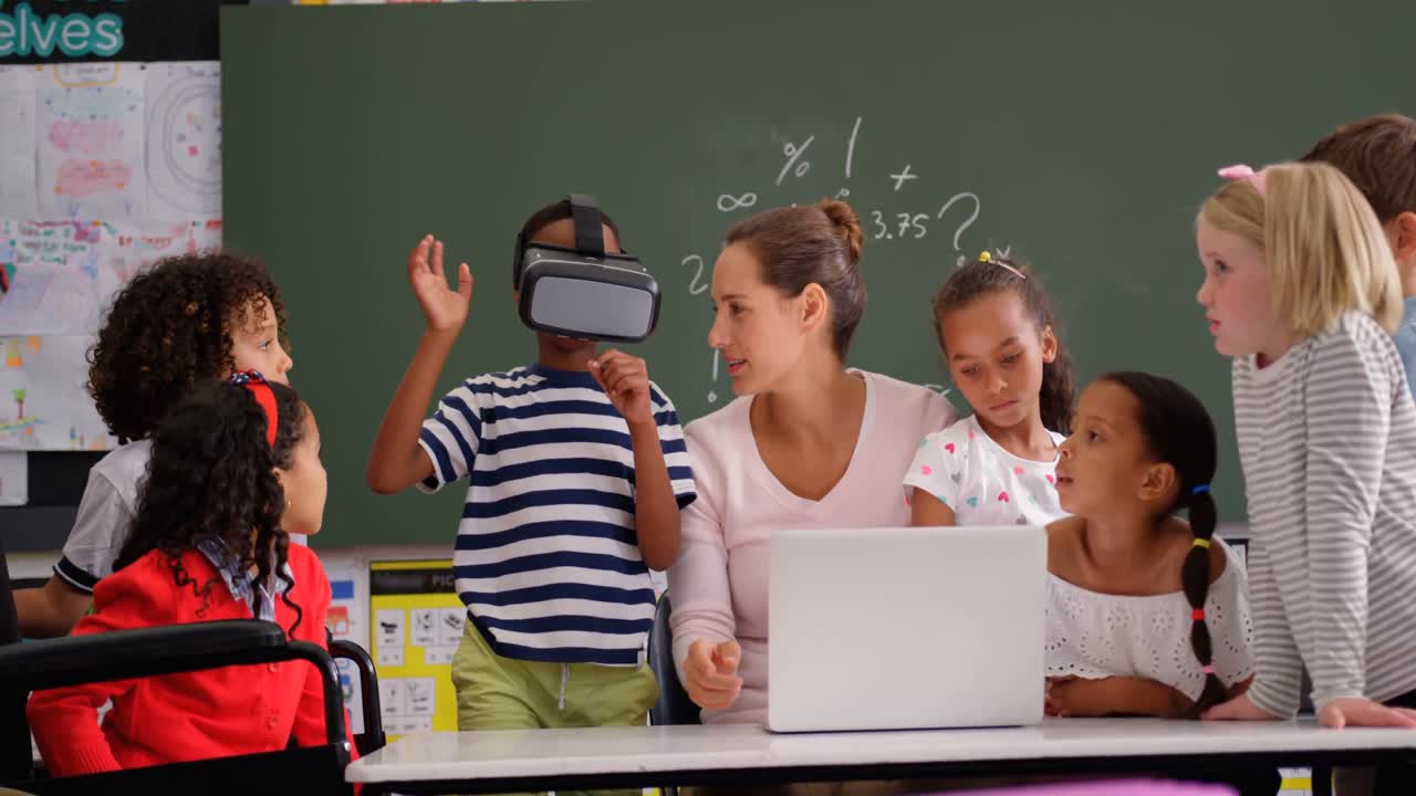 Front view of African american schoolboy using virtual reality headset with teacher and classmates i