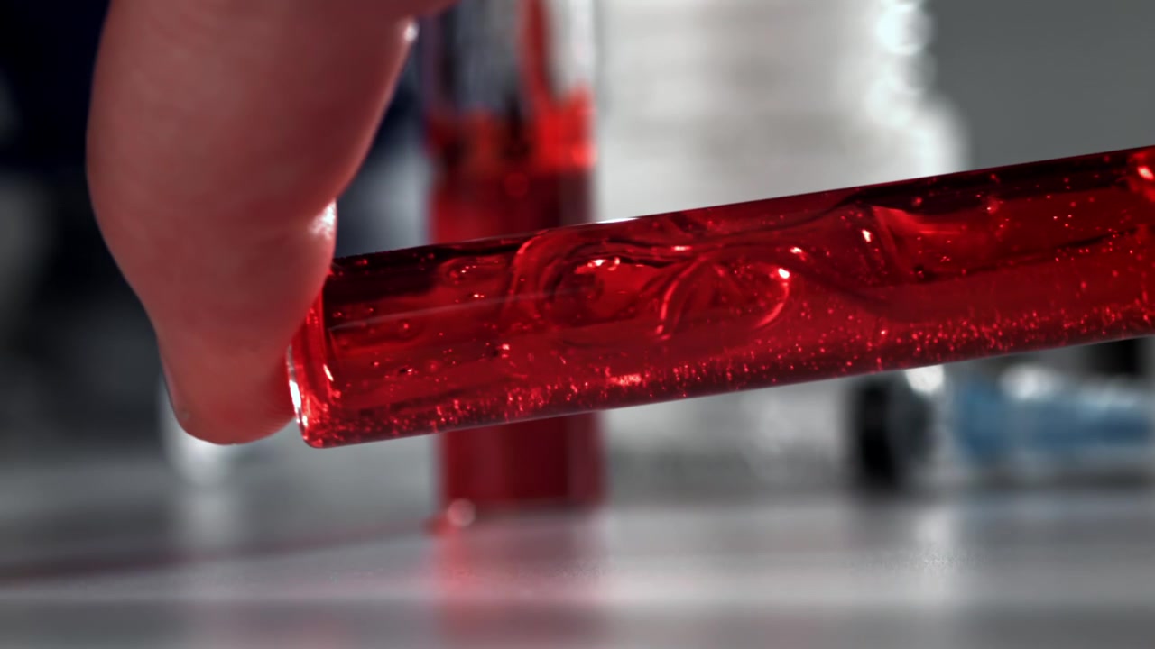 Close-up of Hand Holding Test Tube with Swirling Red Liquid