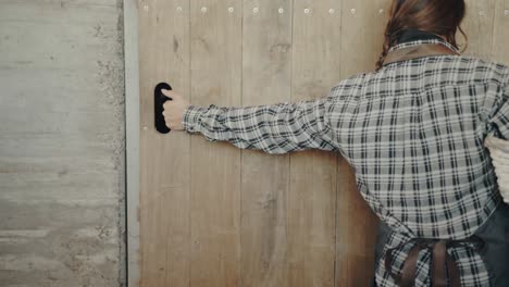 female farmer opening the gate of a cowshed in slow motion