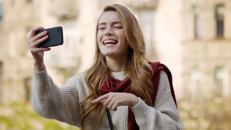 Happy-girl-having-video-call-by-phone-outdoors.-Cheerful-woman-using-phone