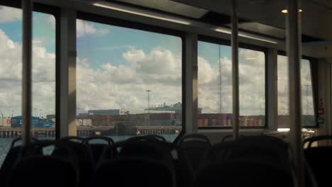 view from a ferry of a busy port with cargo ships and containers