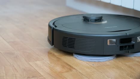 an autonomous robot vacuum cleaner spins and cleans a hardwood floor in a home living room