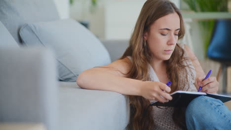 Woman-Writing-in-Notebook-at-Home