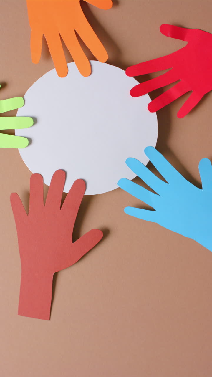 Vertical video of hands touching circle made of colourful paper on brown background with copy space