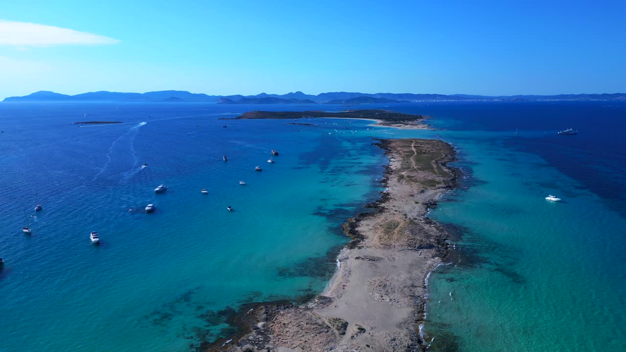 Formentera island coastline with clear turquoise water and anchored boats under a blue sky. overflight flyover panorama overview drone