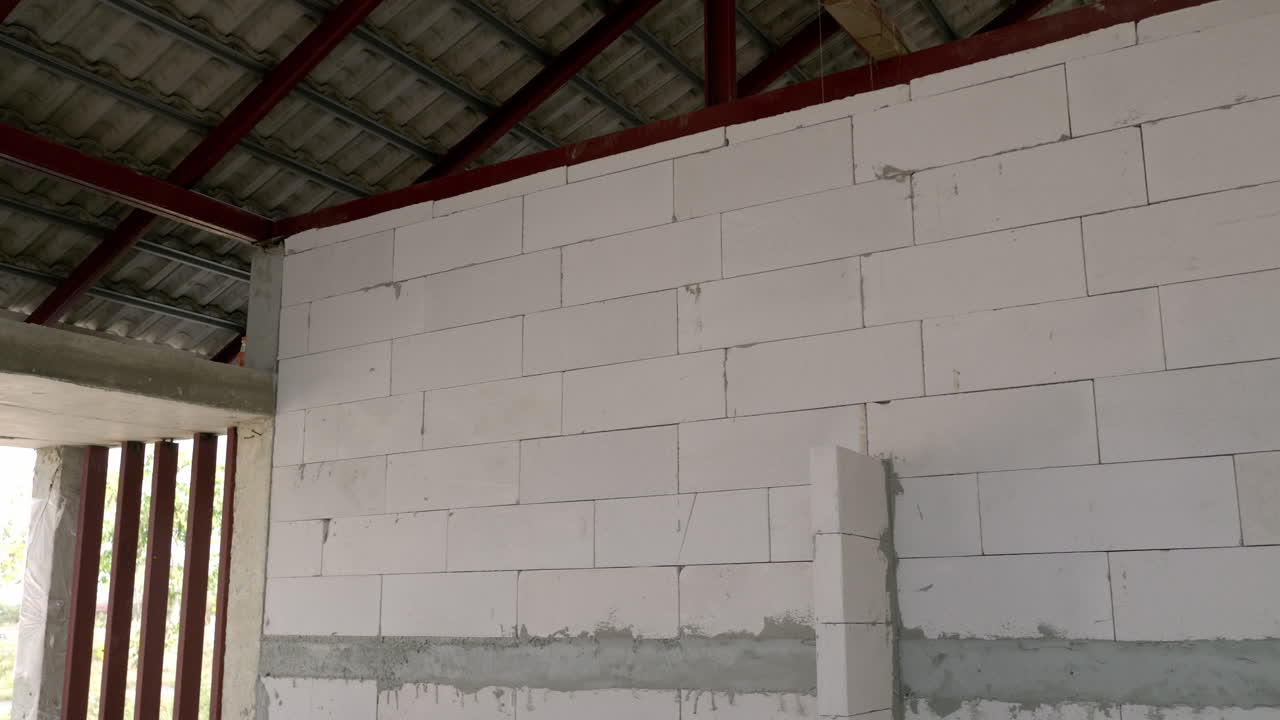 Panning from the left to the right, showing some hollow blocks stacked up together for a wall in a building under construction.