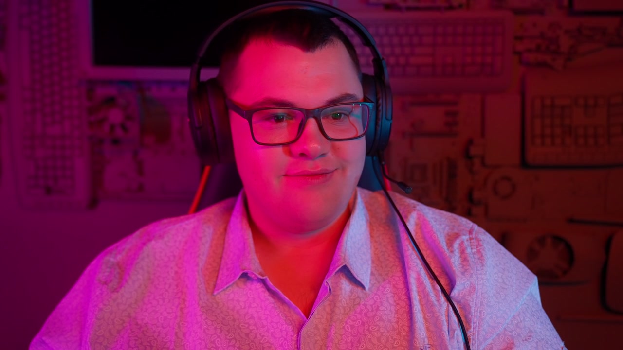 Mladý muž se sluchátky se usmívá v neonově osvětlené místnosti