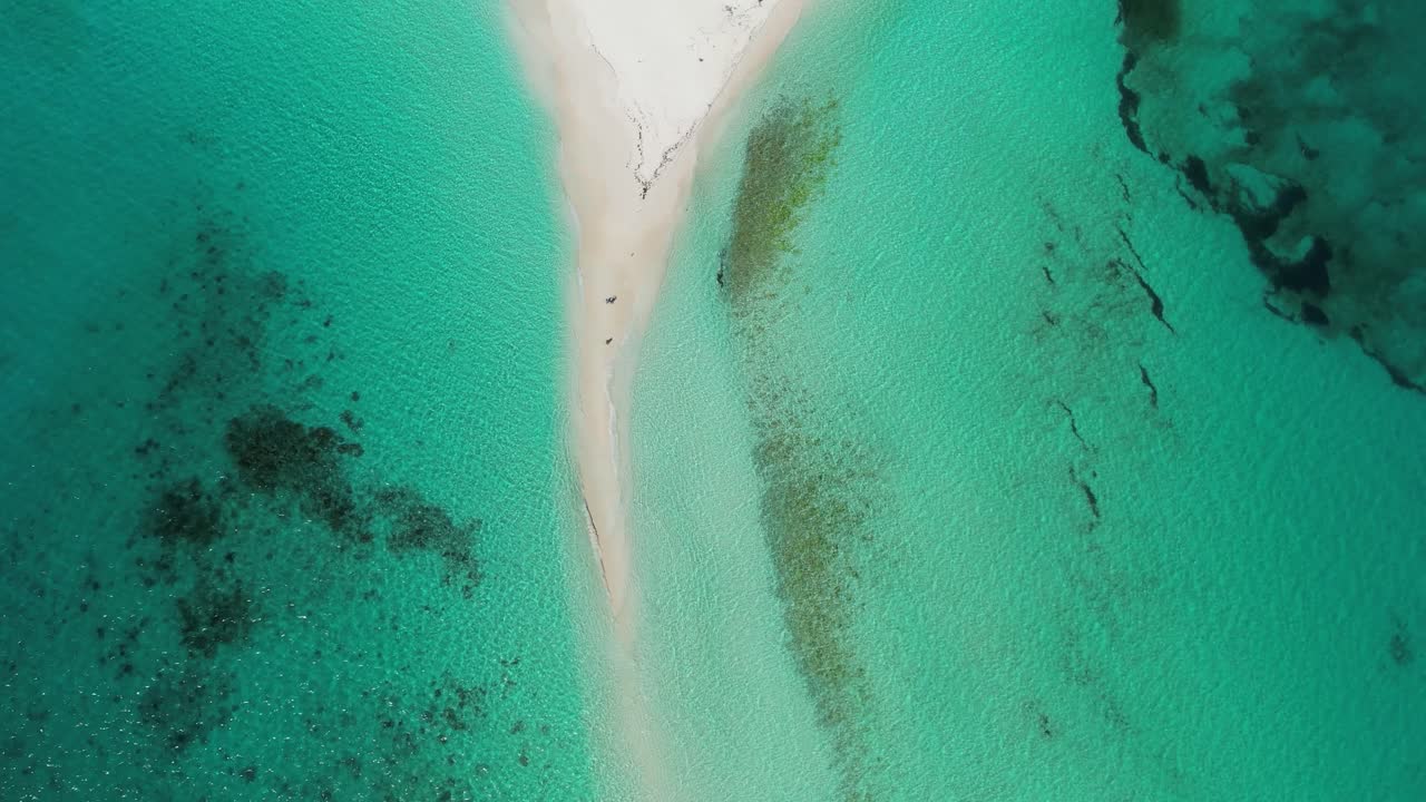 A narrow sandy path dividing turquoise waters, aerial view