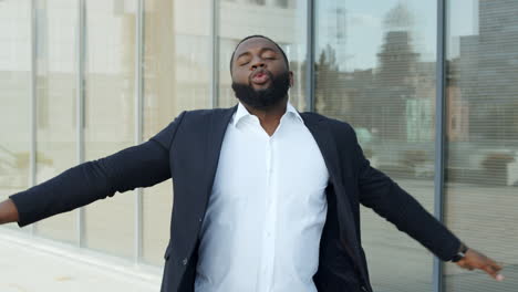 african businessman dancing in city. business man celebrating success on street.