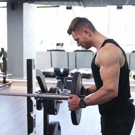 athletic man in the gym. muscular man putting heavy plates on barbell and lifting in gym
