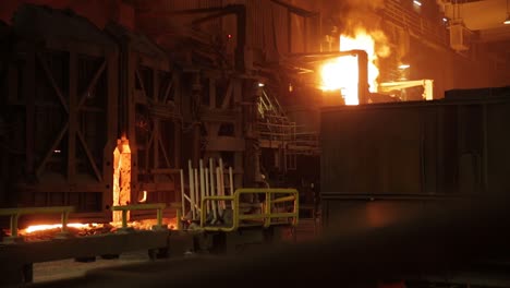 Molten-metal-pouring-in-a-dimly-lit-steel-mill,-highlighting-intense-industrial-processes