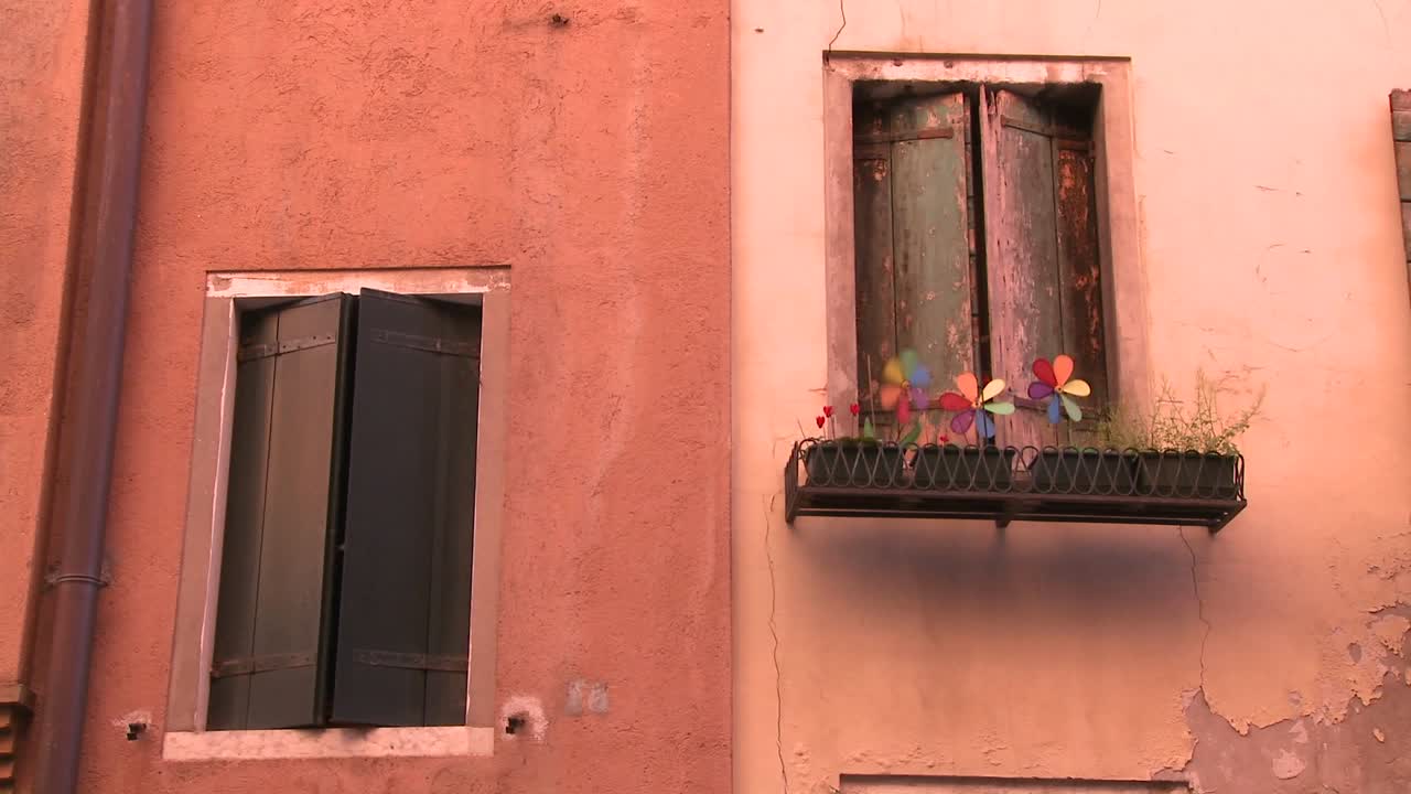 molinetes giran en una sembradora fuera de una vieja ventana en venecia italia 1