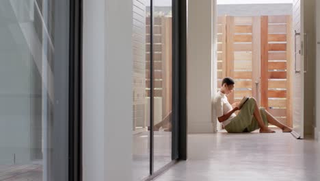 african american woman sitting in doorway, reading book and drinking tea, slow motion