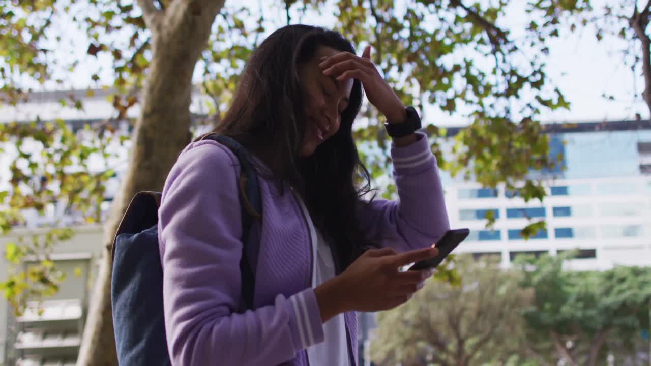 Asian woman smiling while using smartphone standing in the park