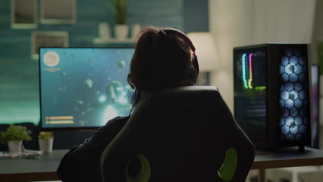 vista trasera de un jugador profesional digital jugando un videojuego de disparos espaciales en línea
