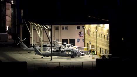 military helicopters in a hanger at night lit up