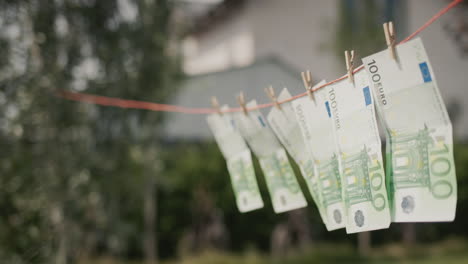 several banknotes of one hundred euros are drying on a clothesline. money laundering concept. side view