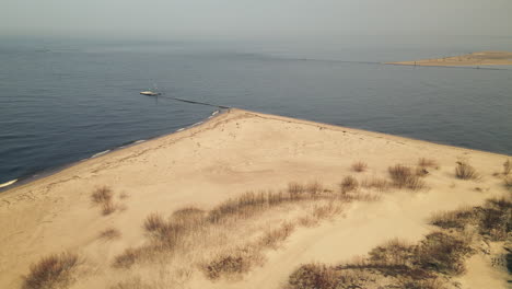 toma aérea de aves que muestra la costa arenosa con olas salpicadas y un amplio mar báltico en el fondo