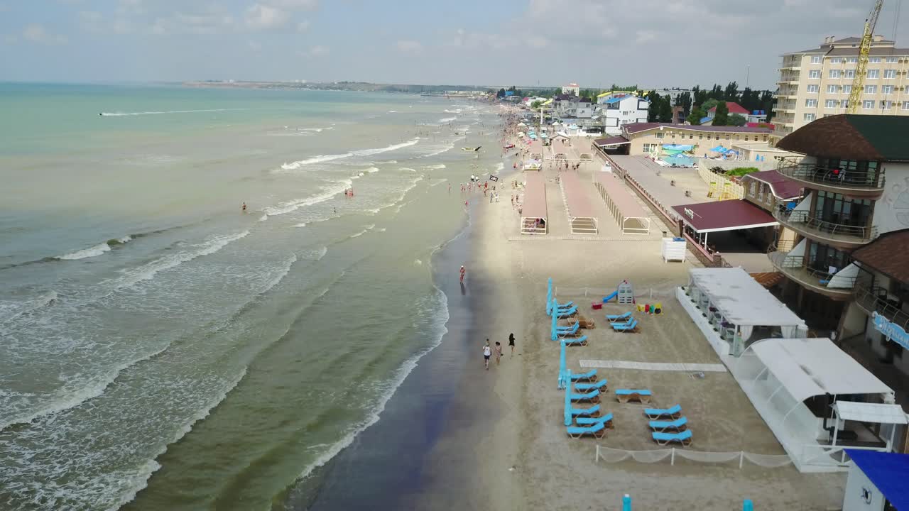 Aerial view of beach with tourists, sunbeds and umbrellas at a luxury hotel. Sea travel destination.