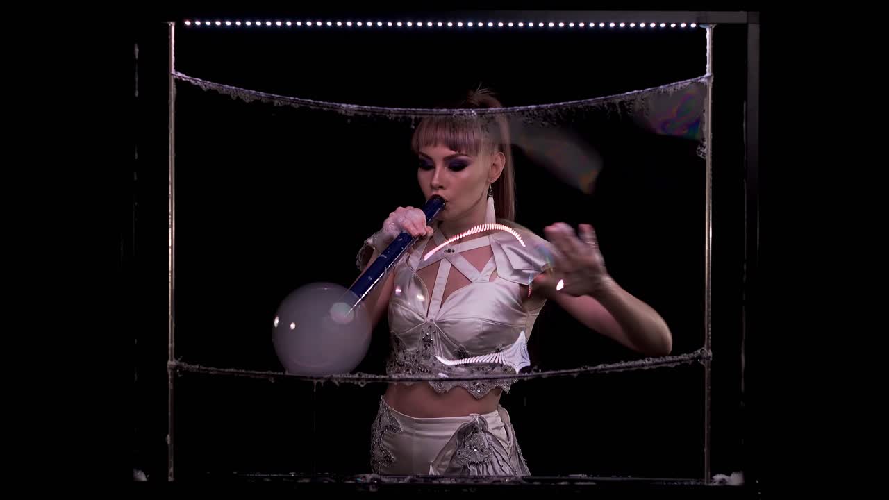 niña hace trucos con pompas de jabón, sopla una gran burbuja con humo