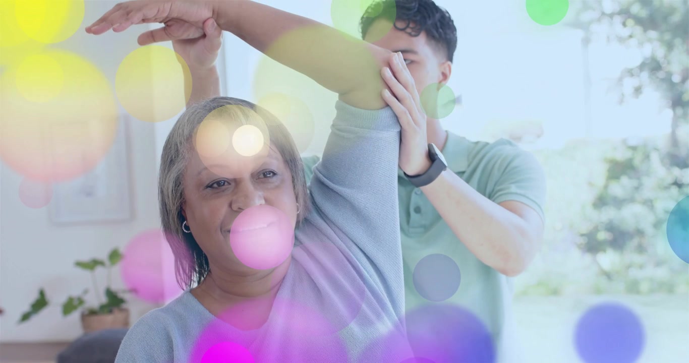 Mujer mayor levantando el brazo, hombre con reloj guiando el estiramiento del brazo para rehabilitación, con superposiciones de color apareciendo.