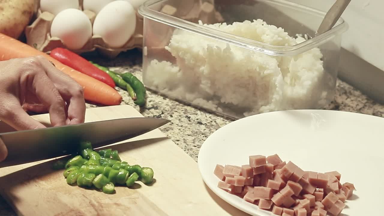 Hands chopping green chilies in a kitchen counter showing the preparation of ingredients for cooking, candid moment of daily home life