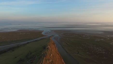 toma aérea de la costa británica, avanzando hacia el mar, tomada mientras el sol se ponía