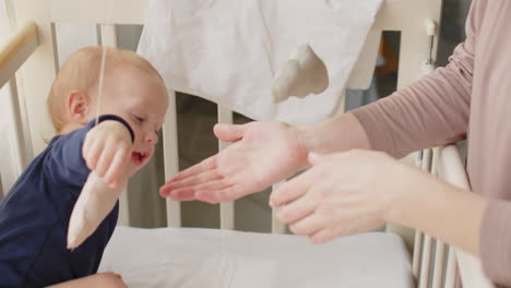 cute baby boy playing with toys in crib