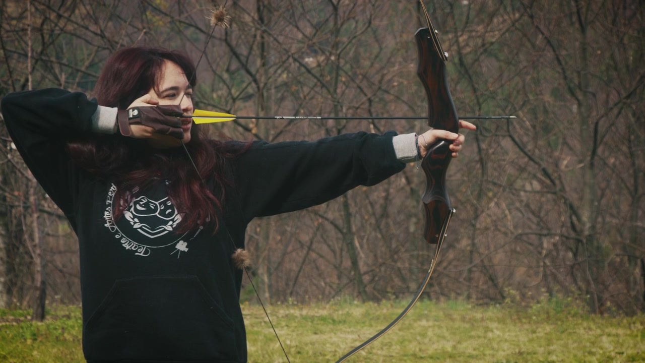 Young woman pulls an arrow from a bow and prepares to shoot