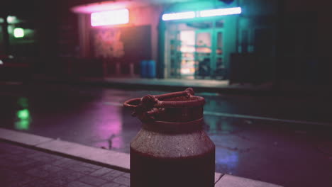 a rusty milk can on a dark, urban street