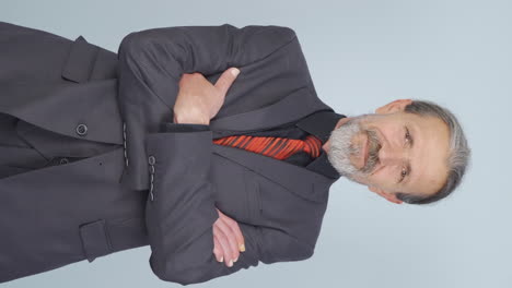 Vertical-video-of-Old-businessman-with-arms-folded-and-laughing-at-camera.