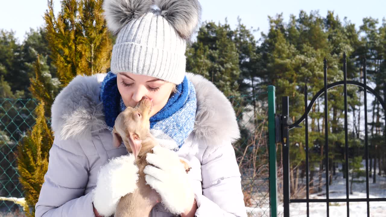 mujer jugando con su pequeño perro fuera del invierno