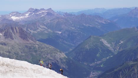 3 people are walking on a line connected with ropes on a dangerous glacier in the alps of france near mont blanc on a clear blue day in the mountains