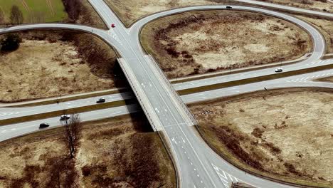 Carretera-Rural-Rotonda,-Coches-Conduciendo-A-Lo-Largo-De-Un-Paisaje-Terroso-Seco,-Vista-Panorámica-Aérea-De-Drones,-Cruce-De-Caminos-Asfaltados