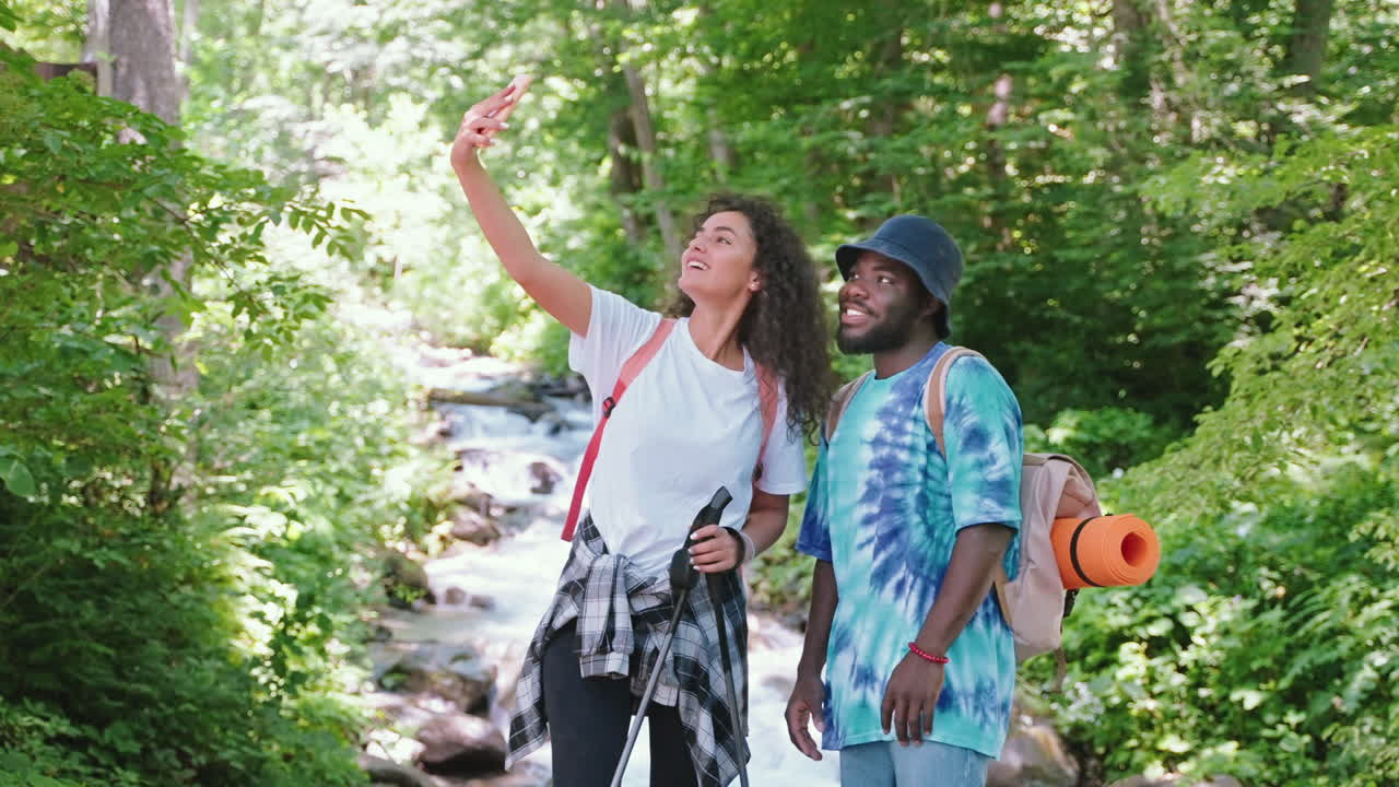 una pareja feliz caminando y tomando una selfie en un bosque