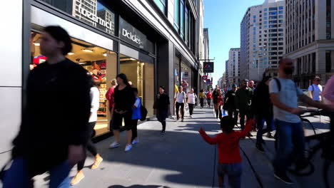 people and a child walking on a busy city street with shops