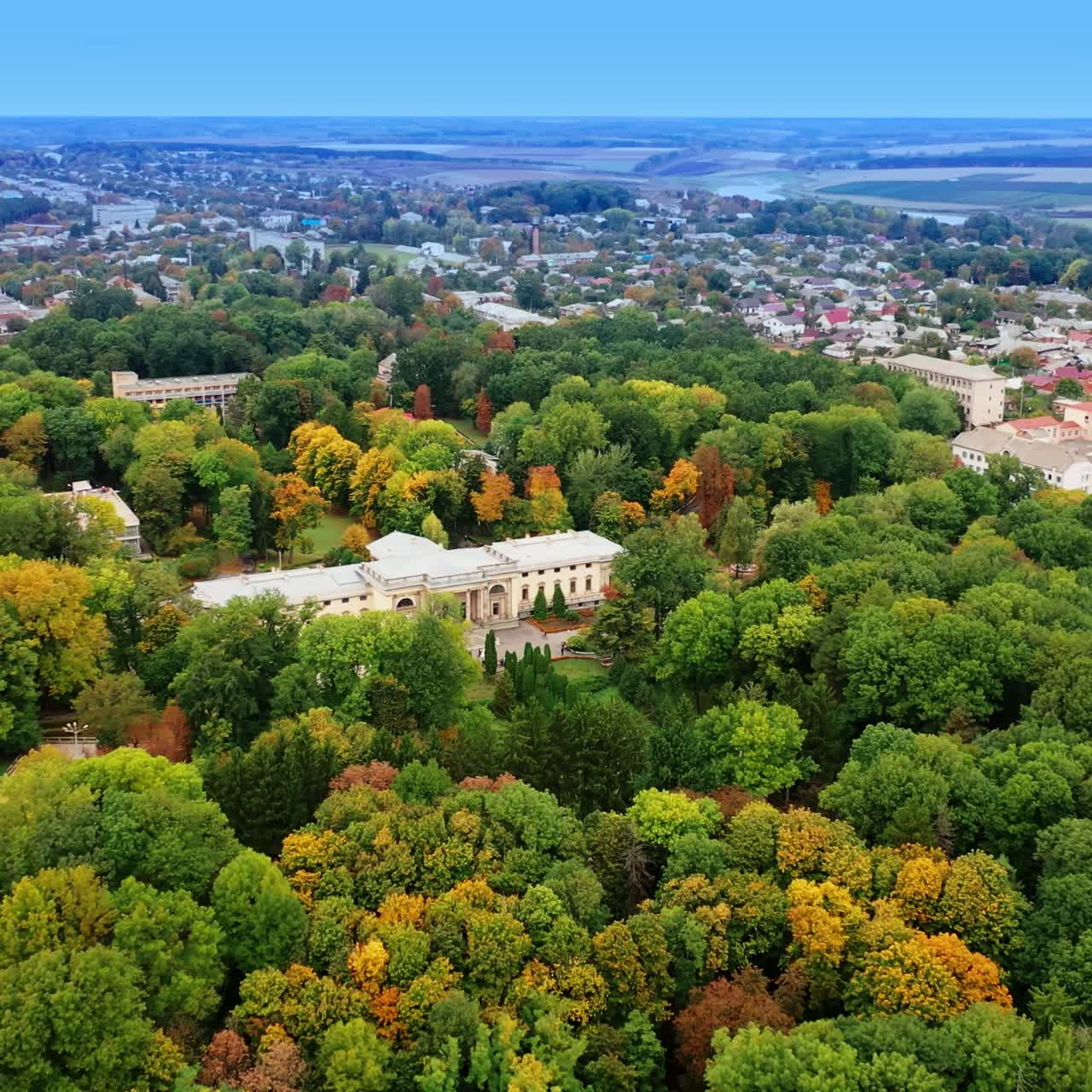 Splendid view of the green park growing around beautiful palace. Provincial cityscape at backdrop of hazy horizon