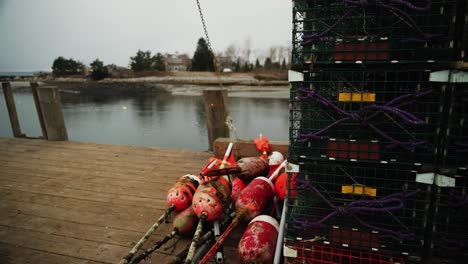 Lobster-traps-and-fishing-buoys-on-pier-in-Maine-tilting-wide-shot