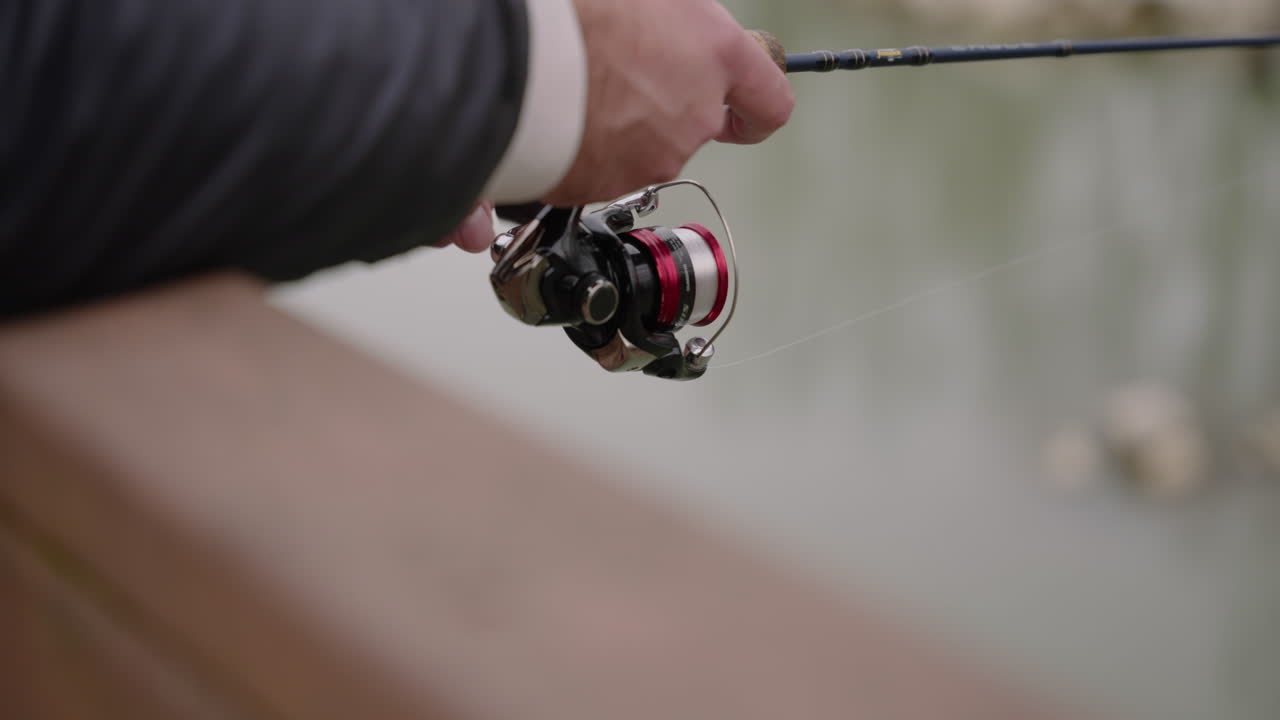 Close Up of fisherman's hands reeling in his fishing rod