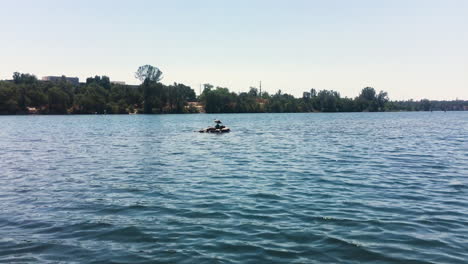 A-canoe-passes-a-lone-bird-as-it-sits-in-close-proximity-perched-on-top-of-rocks-in-a-river