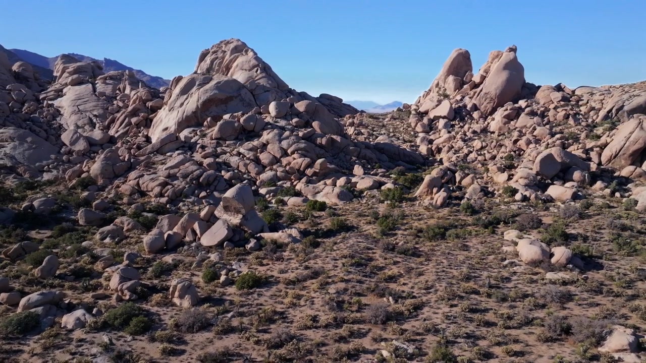 Formazione rocciosa collinare aspra, dune di Kelso Pinto Basin, Parco Nazionale Joshua Tree California, ripresa aerea con drone, alberi di Yucca, Contea di San Fernando, deserto del Mojave e del Colorado, cielo blu, pomeriggio soleggiato, movimento circolare a destra