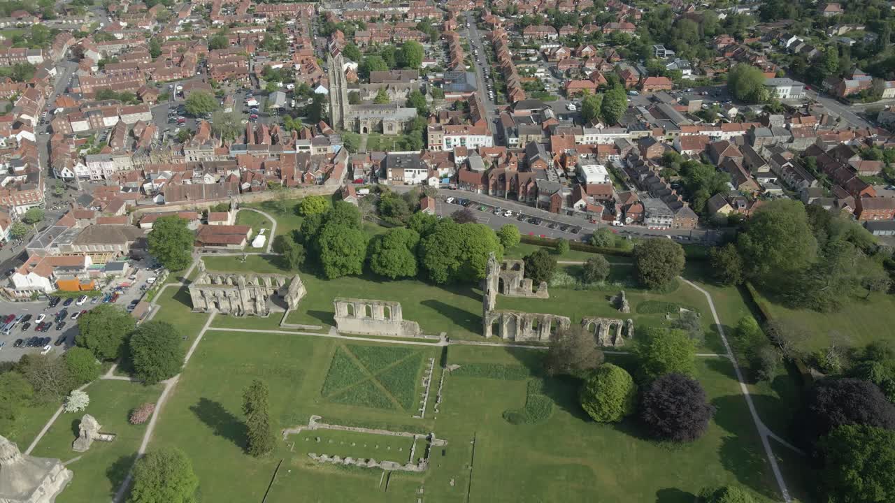 Aerial view of the Glastonbury Abbey ruins an 8th century monastery and gardens. Drone moving to the left showing the abbey ruins and Glastonbury town in the backgroung. 4K, 60fps.