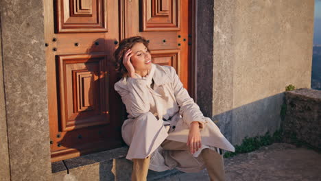 relaxed girl sitting doorway at evening sunlight. chic lady traveler weekend