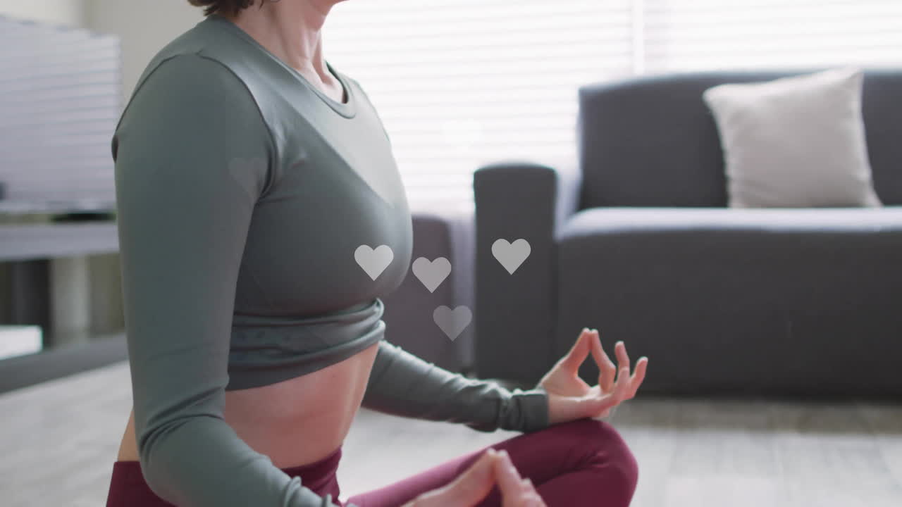 Woman sitting cross-legged on floor in living room, with floating heart icons showing health data