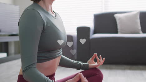 woman sitting cross-legged on floor in living room, with floating heart icons showing health data