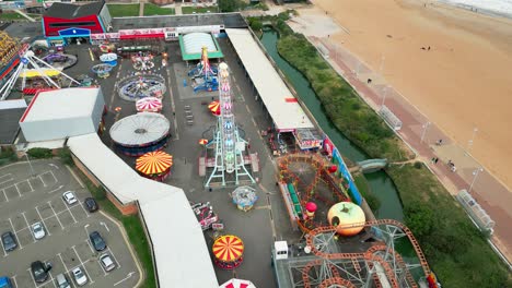 Typical-English-seaside-resort,-shot-using-a-drone,-high-aerial-viewpoint-showing-a-wide-expanse-of-sandy-beach-with-a-pier-and-crashing-waves