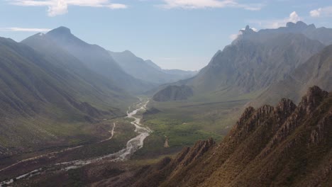 stunning, wide, aerial view of river running through valley lined by steep cliffs and mountains near monterrey, mexico and la huasteca park