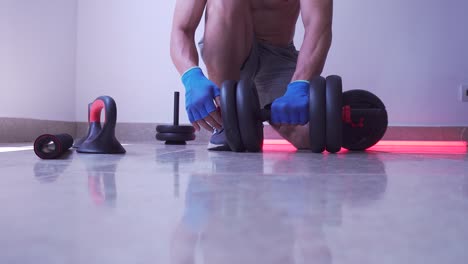 man taking apart dumbbells after weightlifting session