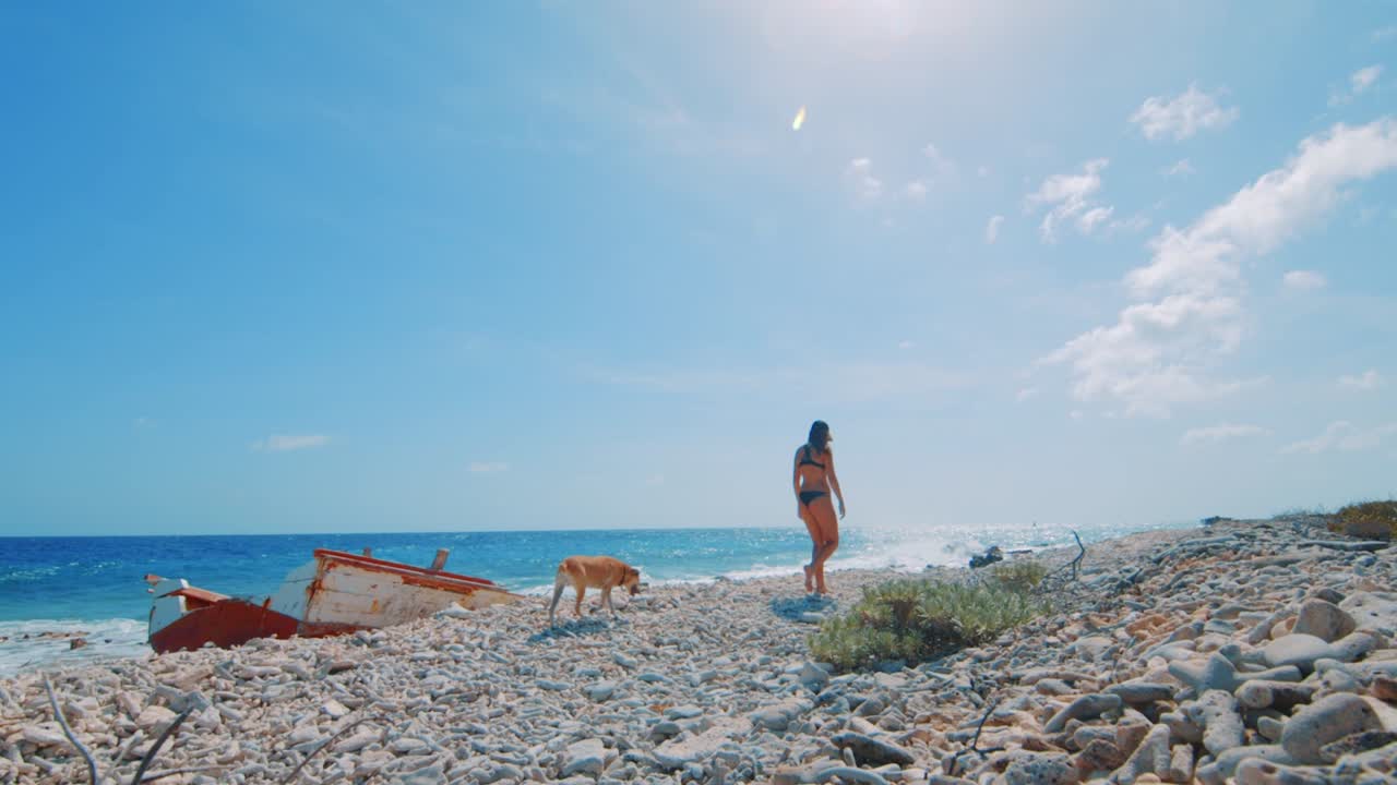 난파선을 타고 바위 해안을 따라 걷는 젊은 여성과 개