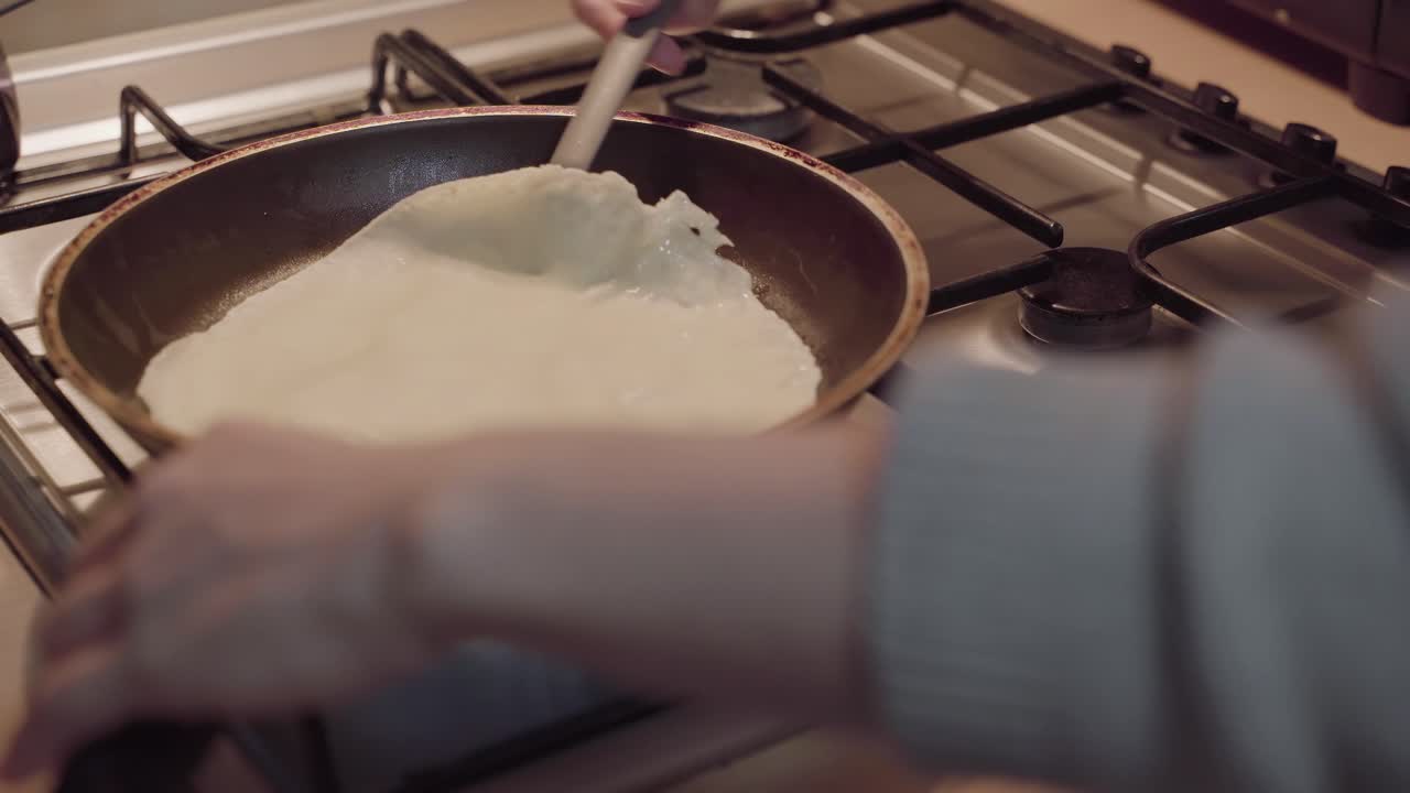 Snu en crêpe på stekepanne på gasskomfyr på kjøkkenet – statisk opptak